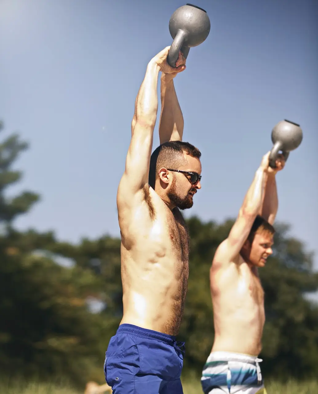 Two men lifting weights in swim trunks
